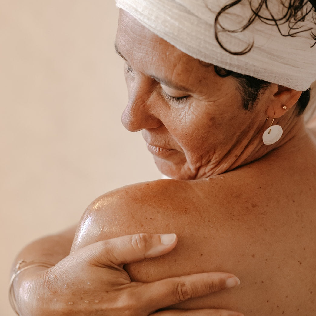 Femme qui applique l'huile sèche Dune sur son épaule