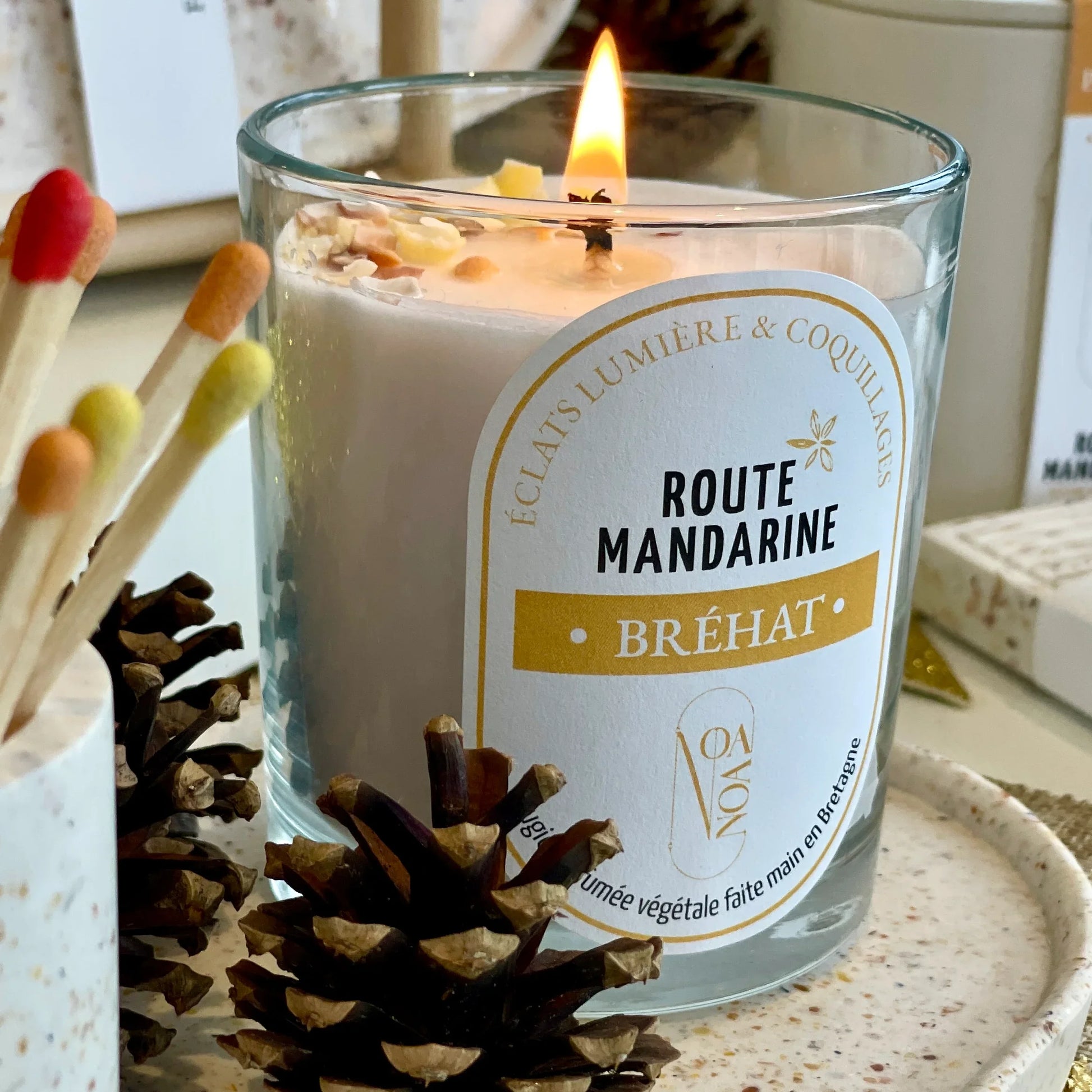 Bougie Bréhat en cire végétale allumée dans un décor blanc et orangé