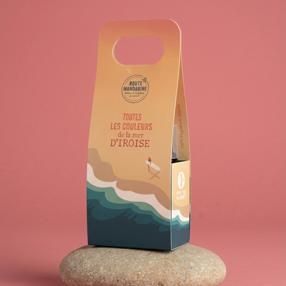 Le coffret dune et écume format voyage sur un galet et avec un fond uni rose