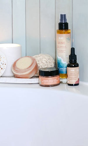 Huile sèche, sérum visage et gommage visage sur le bord d'une baignoire