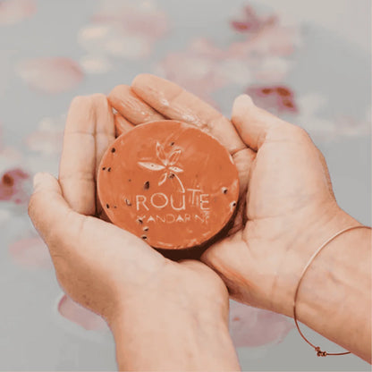 savon samourai dans les mains d'une femme au dessus d'une baignoire avec des fleurs